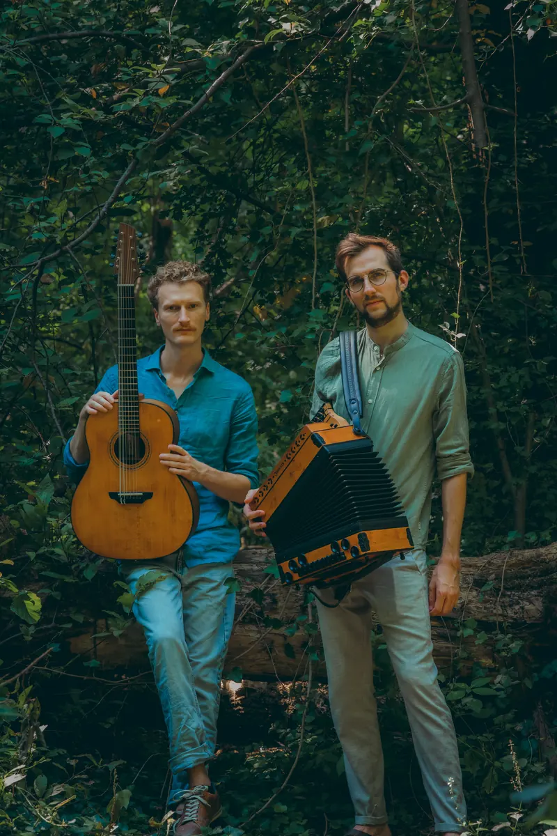 Tim & Jonnic stehend im Wald mit Gitarre und Harmonika