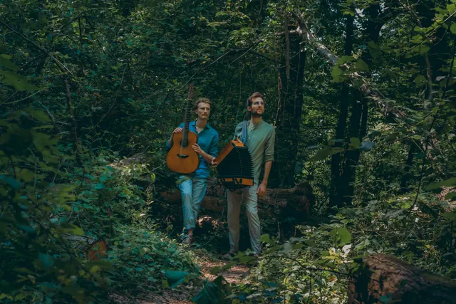 Das Duo mit Instrumenten in einem dichten, grünen Wald