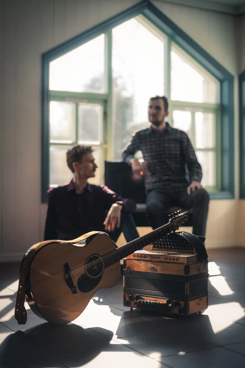 Tim & Jonnic in einem hellen Raum mit hohen Fenstern
